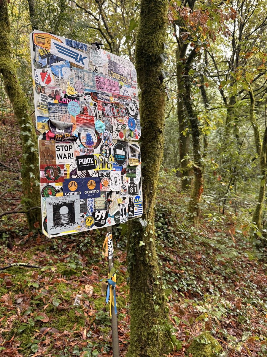 Sticker-covered waymarker in the woods