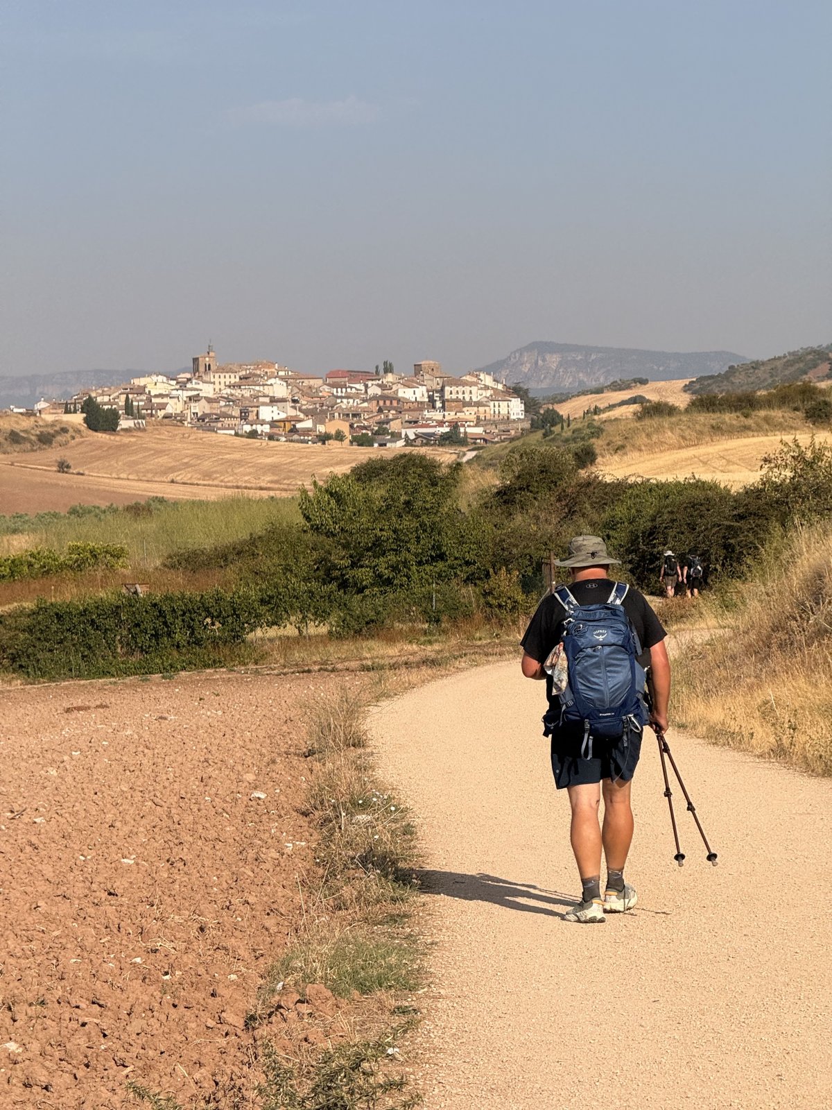 A lone walker approaching a hilltop town