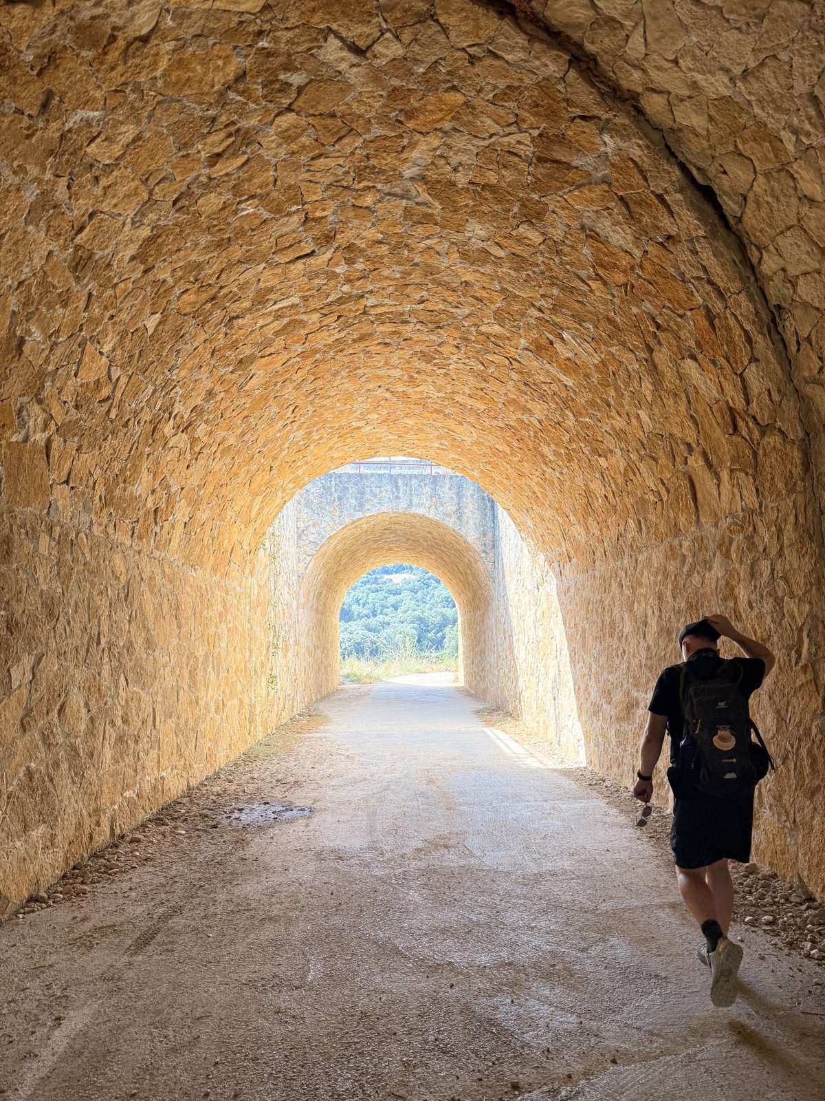 Walking through a stone tunnel on the Camino